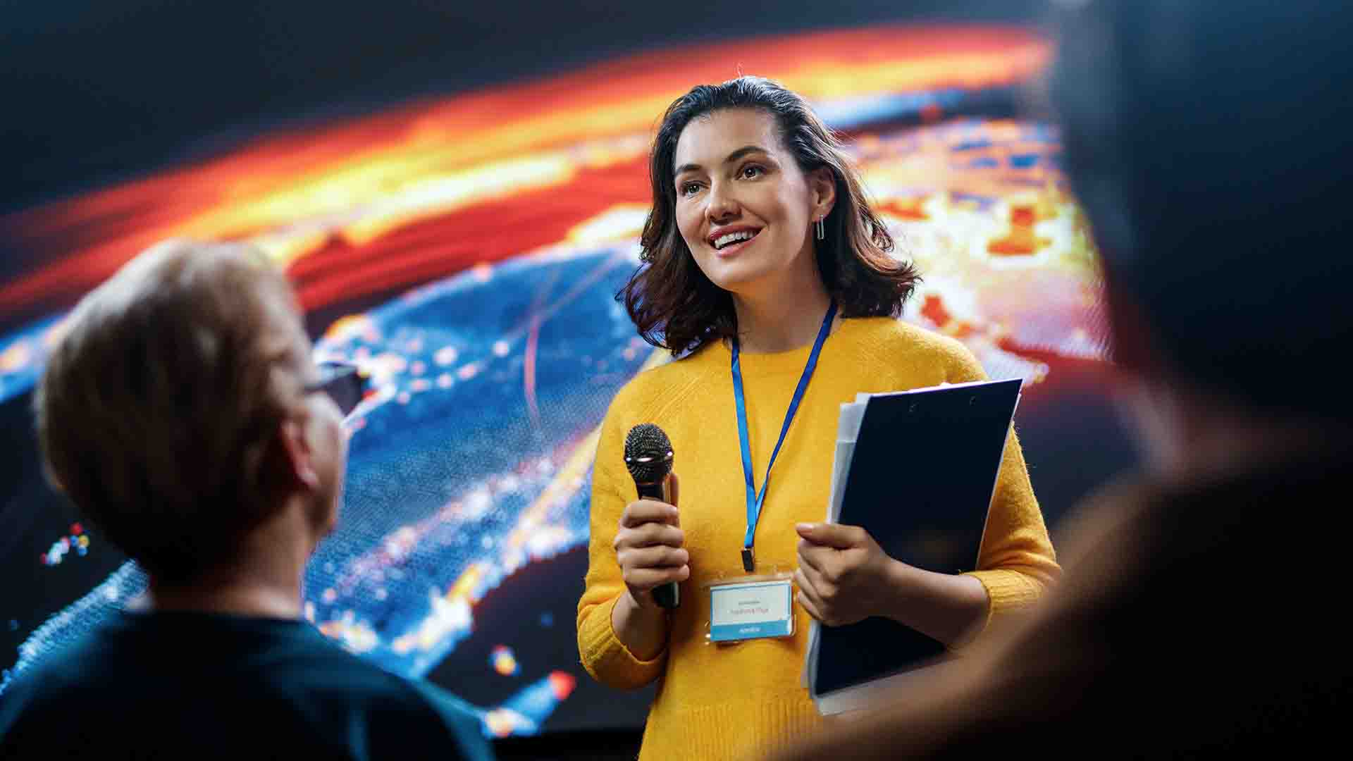 Moderatorin mit Mikrofon auf der Bühne – Eventdreh von LANIZMEDIA