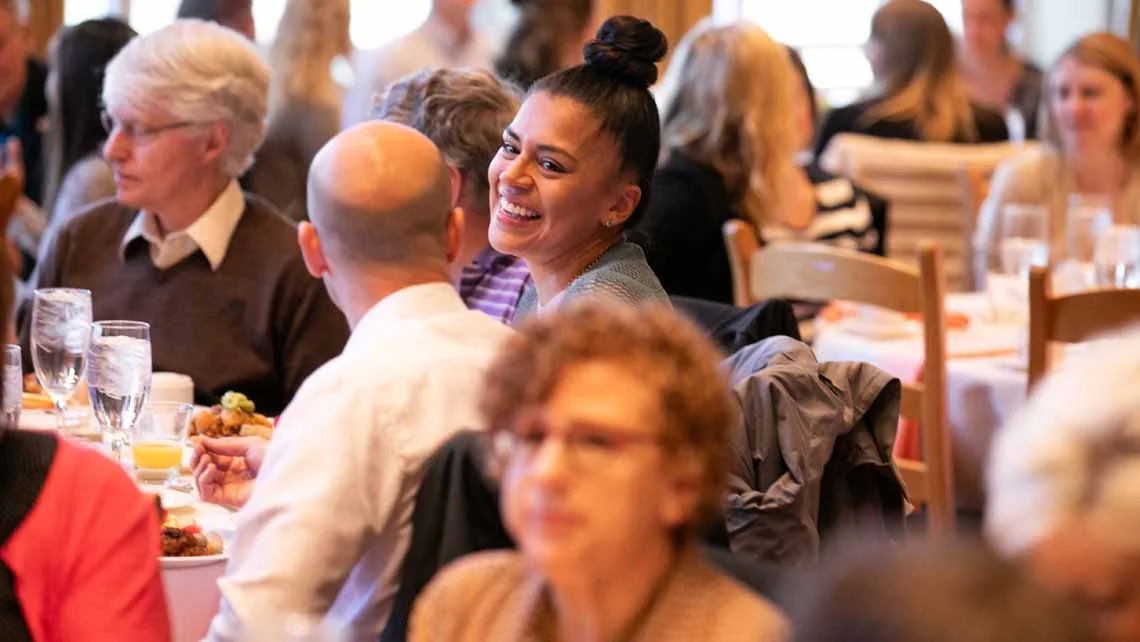 Lachende Gäste bei einem Firmenevent-Dinner an festlich gedeckten Tischen