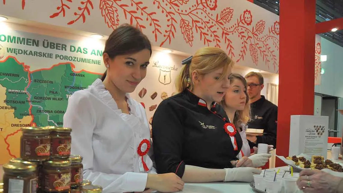 Produktverkostung mit Ausstellerinnen an einem dekorierten Messestand