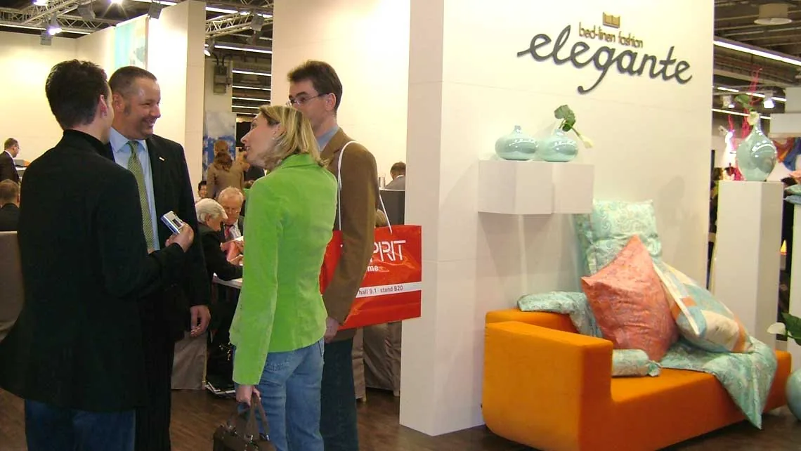 Gespräche zwischen Ausstellern und Besuchern an einem Messestand mit Lounge-Möbeln